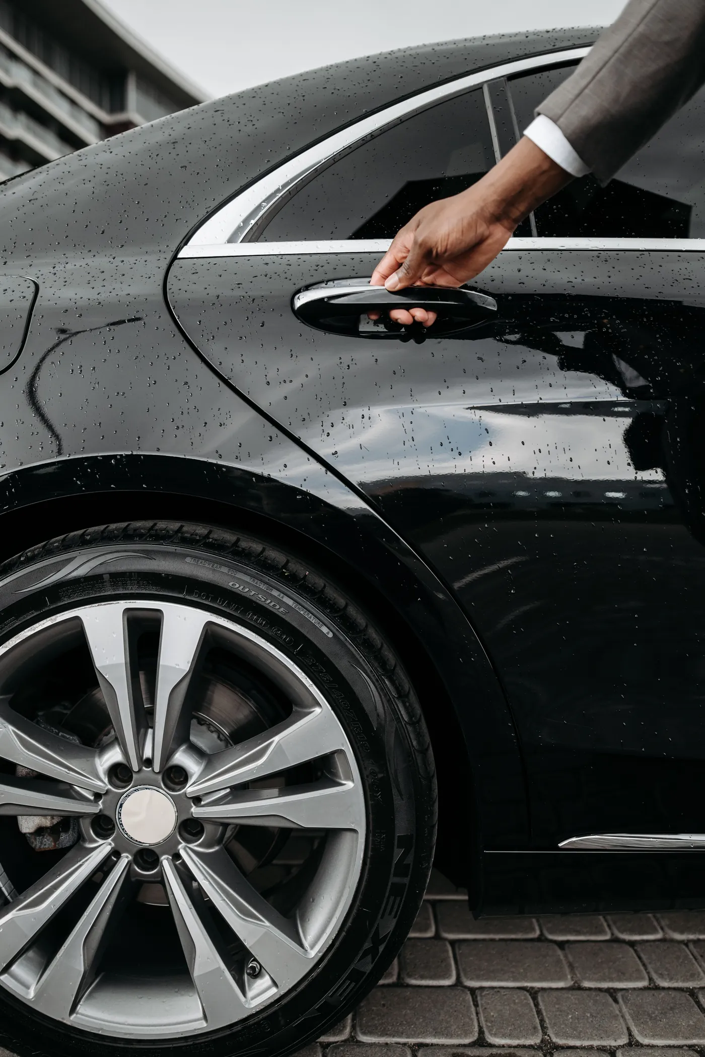 Chauffeur opening a black luxury vehicle door